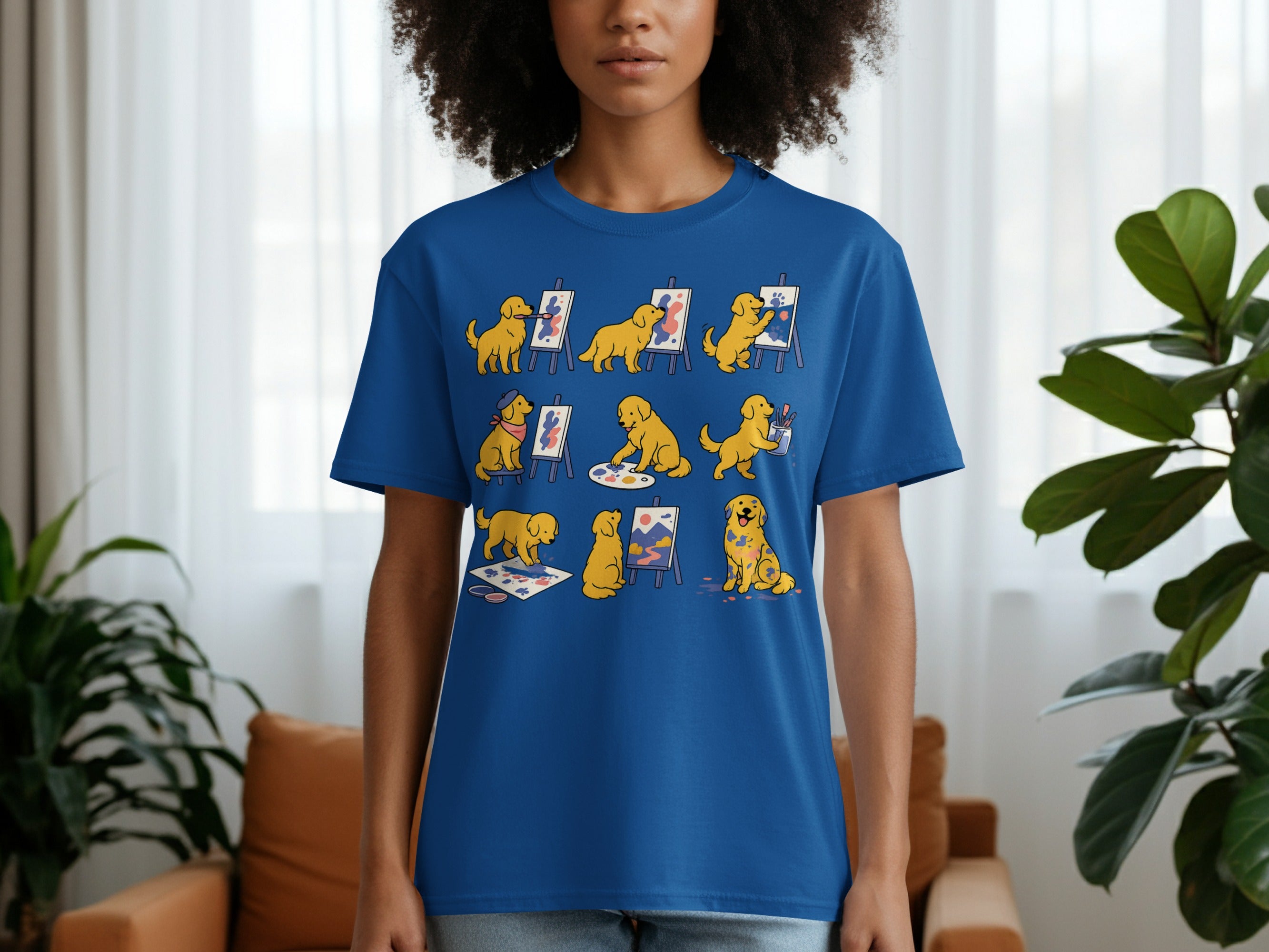 Blue t-shirt with cartoon golden retrievers painting and getting paint on themselves.
