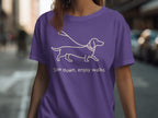 Purple t-shirt with outline of dachshund on leash and text "Slow down, enjoy walks."