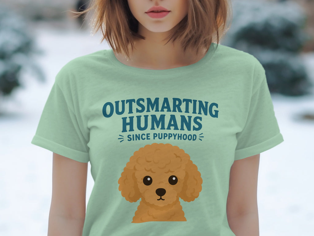 Light green t-shirt with cartoon poodle and "Outsmarting Humans Since Puppyhood" text.
