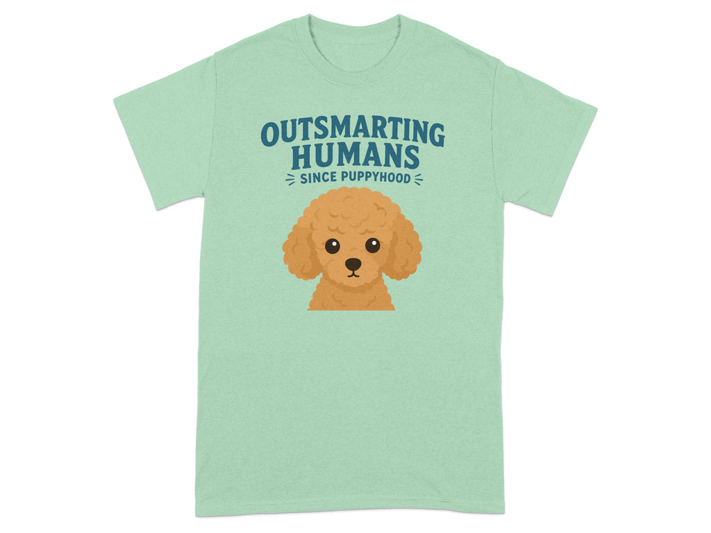 Light green t-shirt with cartoon poodle and text "OUTSMARTING HUMANS SINCE PUPPYHOOD".