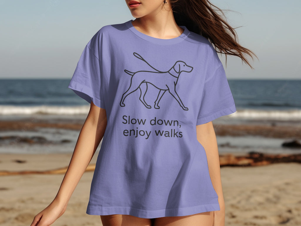 Lavender t-shirt with a line drawing of a dog and the text "Slow down, enjoy walks".