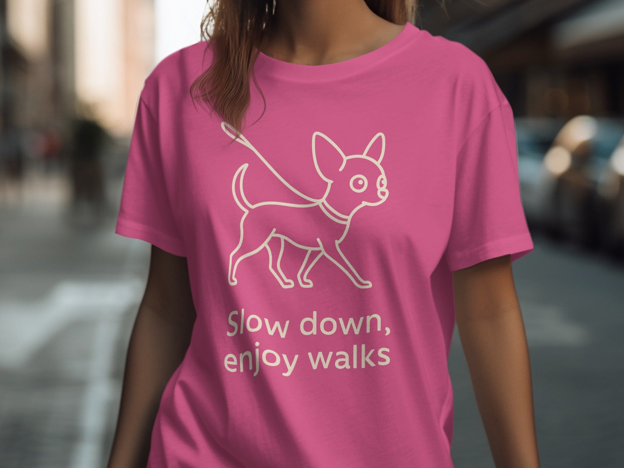 Pink t-shirt with a white outline of a dog on a leash and the text "Slow down, enjoy walks".