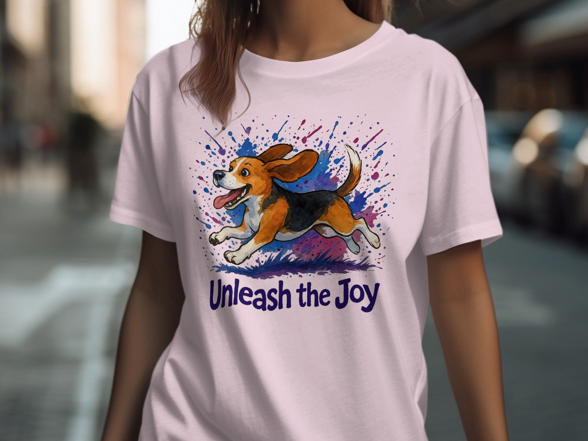 Pink t-shirt featuring a watercolor beagle mid-run with splattered ink and text "Unleash the Joy."