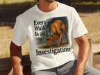 White t-shirt with dog wearing a hat, text "Every Walk Is an Investigation"