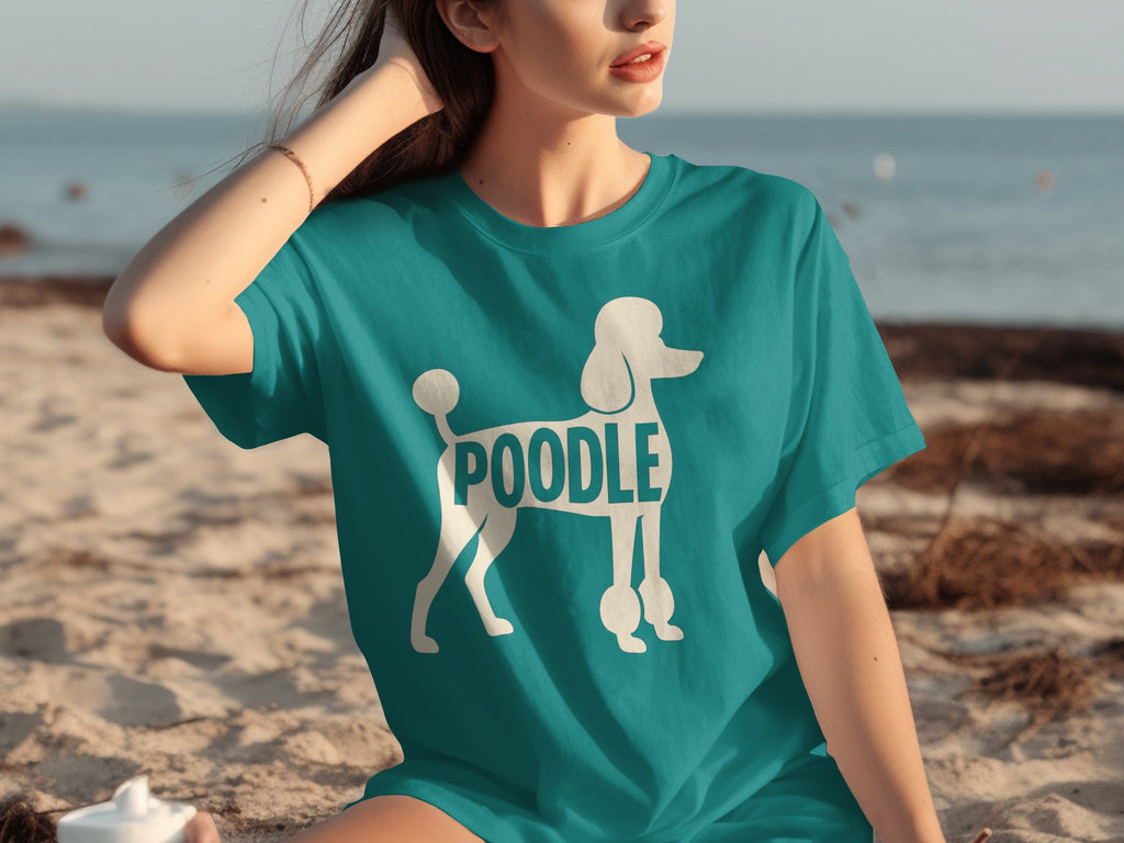Teal t-shirt with white poodle graphic and text on a beach