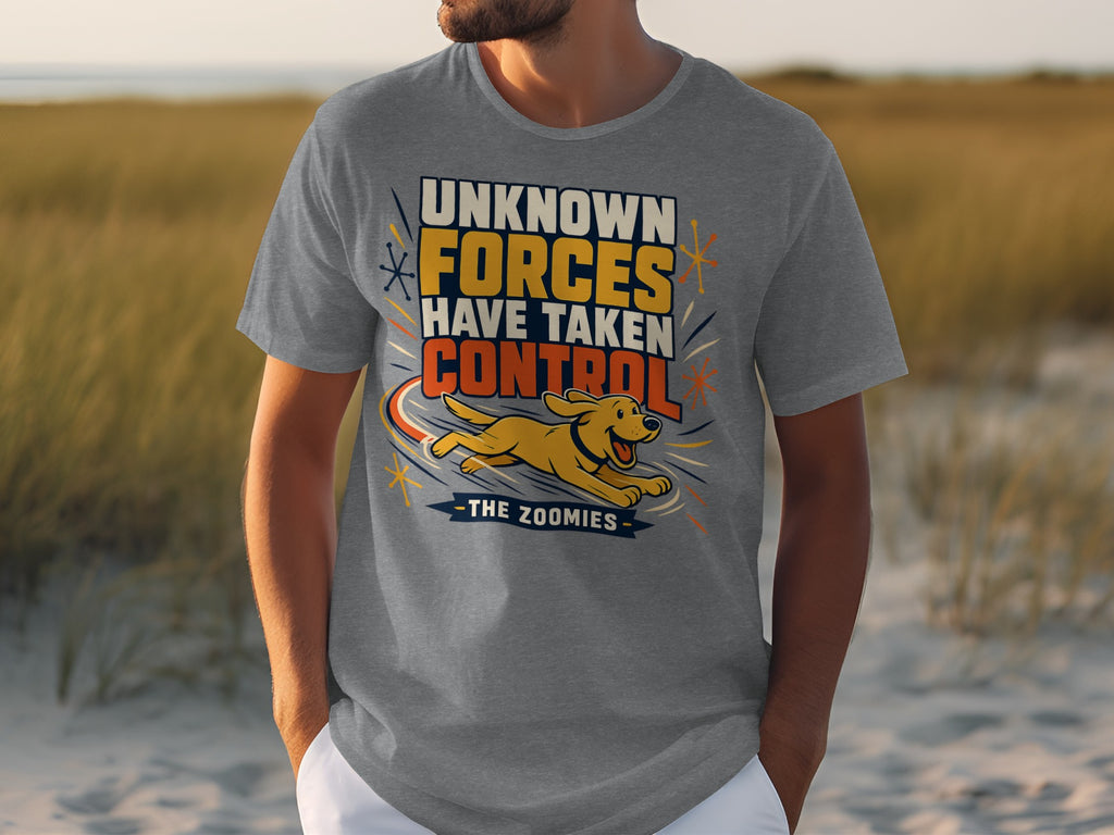 Man wearing grey t-shirt with text "UNKNOWN FORCES HAVE TAKEN CONTROL THE ZOOMIES" and a running dog.