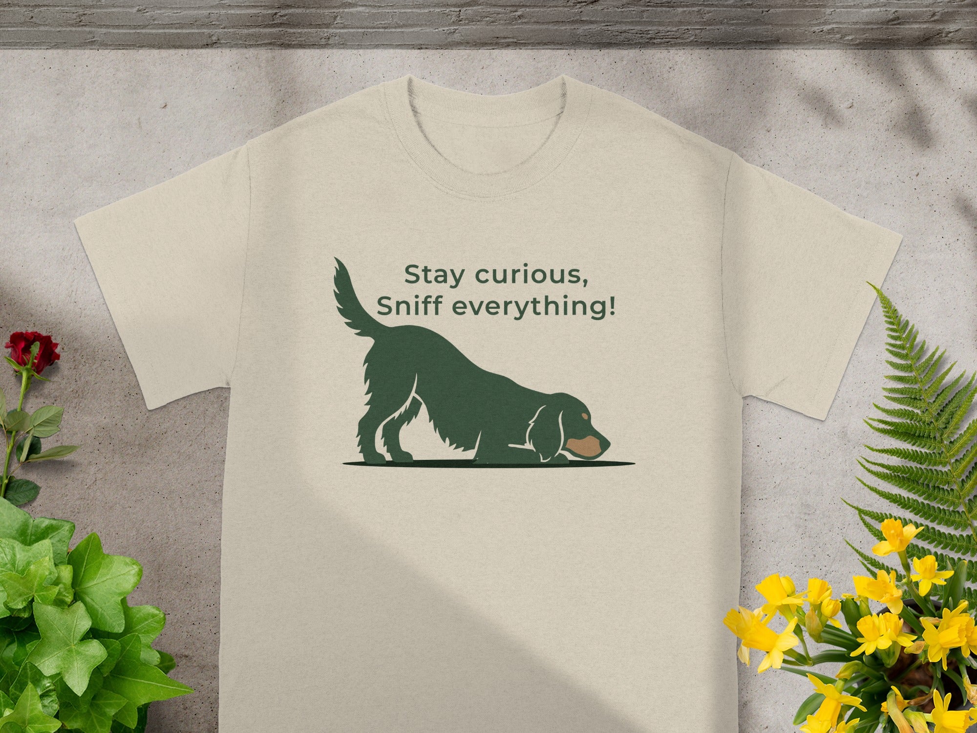 Beige t-shirt with a dark green dog sniffing the ground and text "Stay curious, sniff everything!".