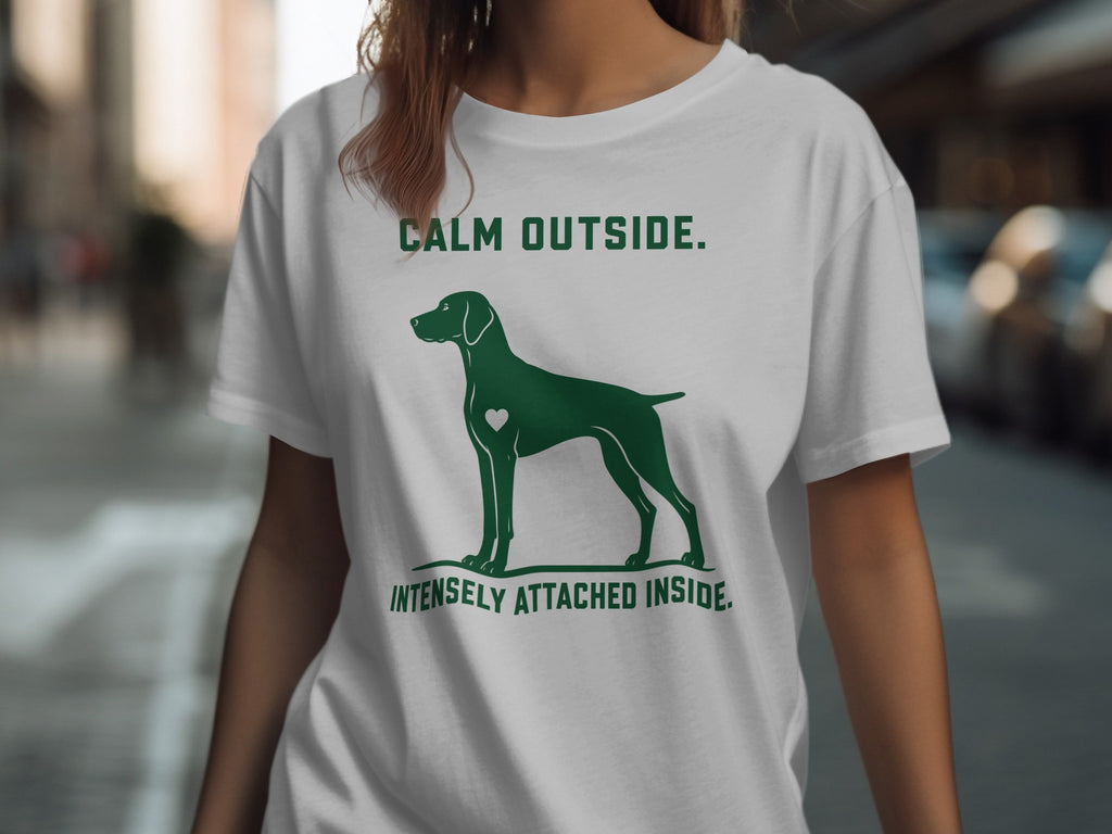 Green dog silhouette with heart on white t-shirt, text "CALM OUTSIDE. INTENSELY ATTACHED INSIDE."