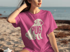 Pink t-shirt with a white pug graphic and "PUG" text on a beach.