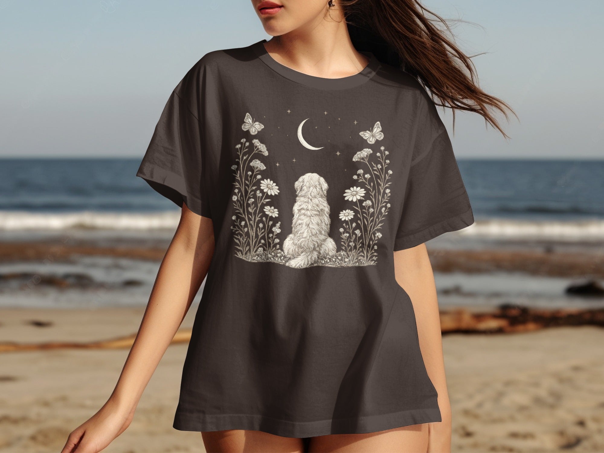 Dark t-shirt with a white graphic of a fluffy dog between flowers, moon, and butterflies.