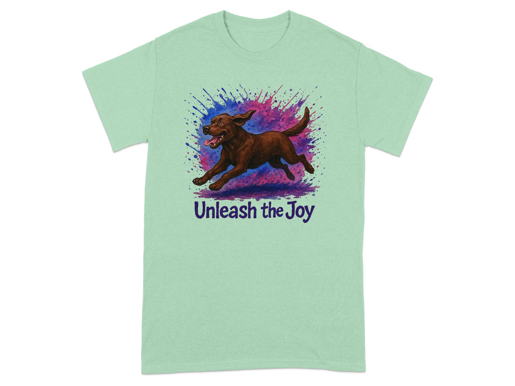 Light green t-shirt with a brown dog running through colorful paint splatters and "Unleash the Joy" text.
