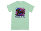 Light green t-shirt with a brown dog running through colorful paint splatters and "Unleash the Joy" text.