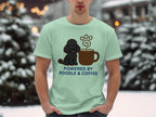 Light teal t-shirt with black poodle and coffee cup graphic, text "POWERED BY POODLE & COFFEE".