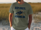 Green t-shirt with "SLEEP ATHLETE. OCCASIONAL DOG." text and dog graphic.