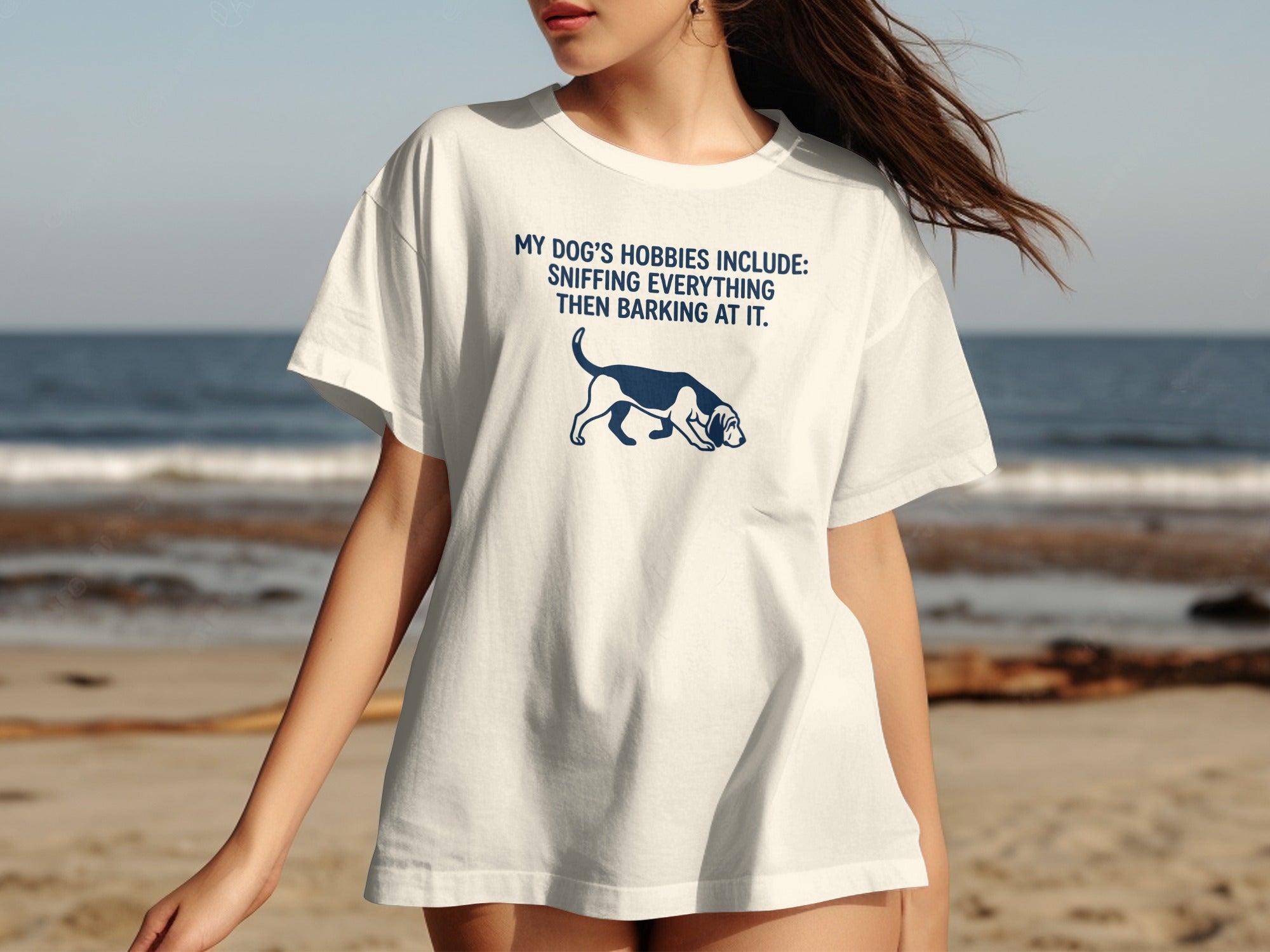 White t-shirt with dark blue text and dog graphic: "MY DOG'S HOBBIES INCLUDE: SNIFFING EVERYTHING THEN BARKING AT IT."