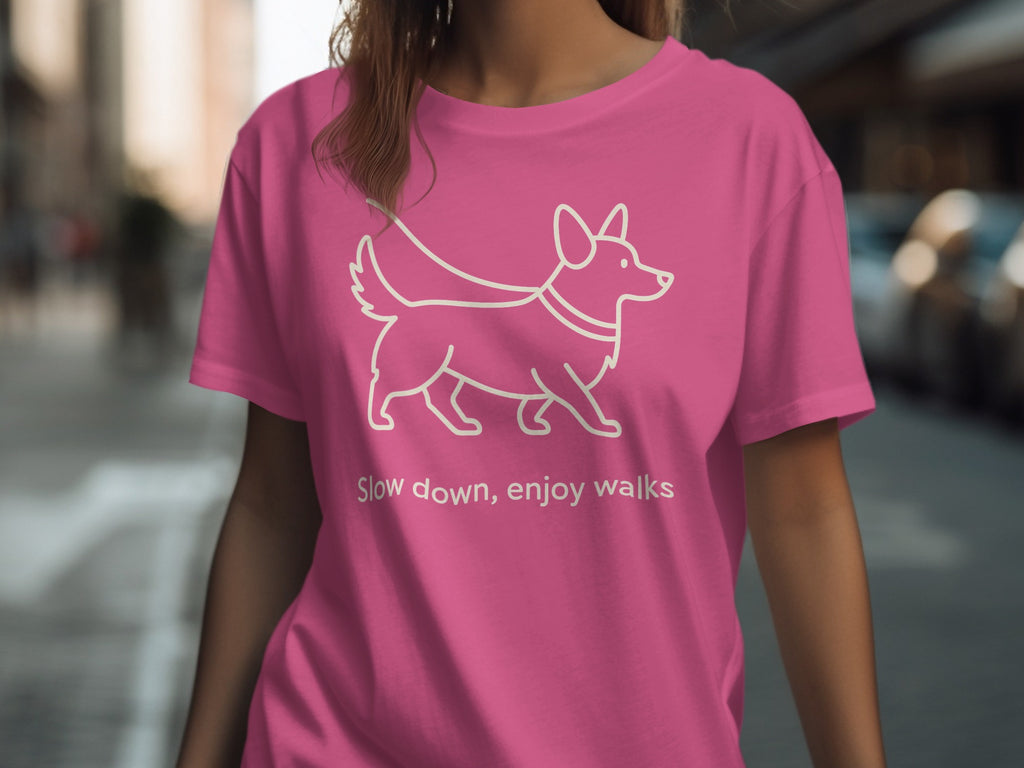 Pink t-shirt with a white outline of a corgi and text "Slow down, enjoy walks".