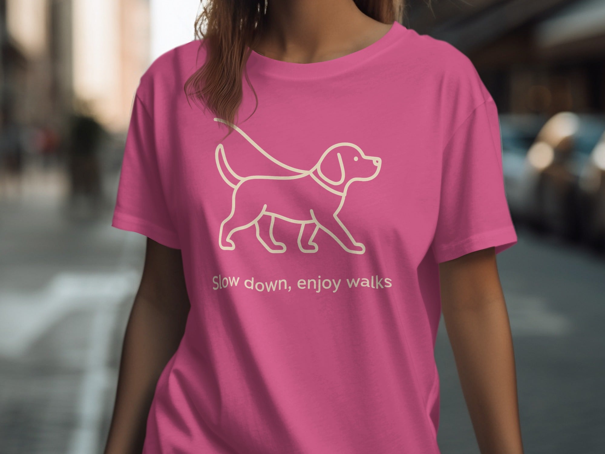 Pink t-shirt with a line drawing of a dog on a leash and text that reads "Slow down, enjoy walks".
