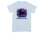 Light blue t-shirt with black dog splattered with pink and purple paint, text "Unleash the Joy"