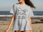 White t-shirt with black line drawing of dog on leash and text "Slow down, enjoy walks".