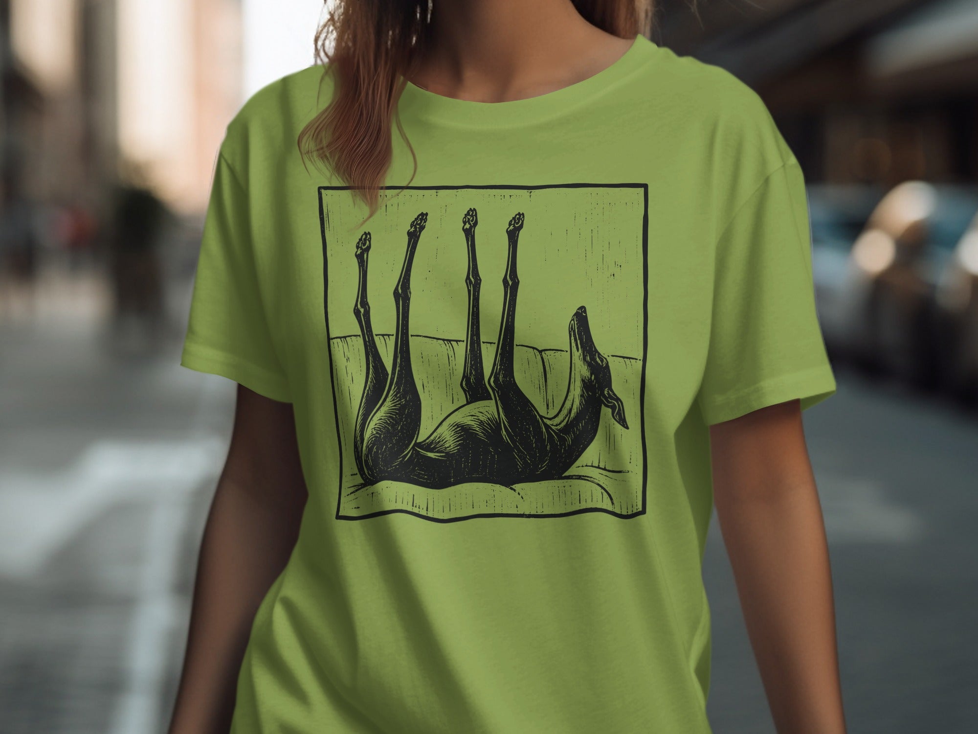 Black line drawing of a dog lying on its back on a couch, printed on a lime green t-shirt.