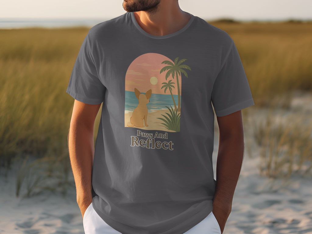 T-shirt graphic of a dog looking at a beach sunset with text "Paws And Reflect".