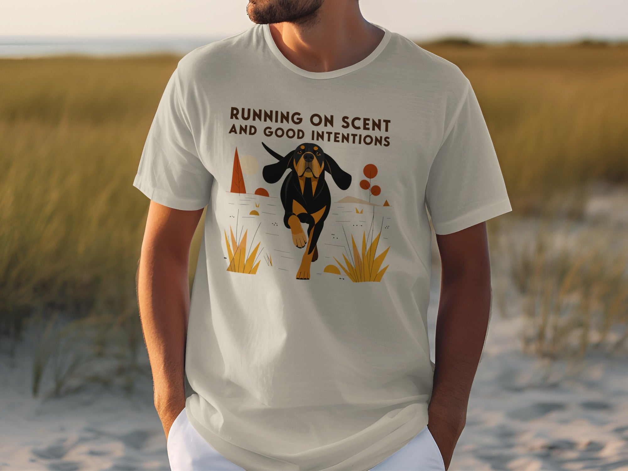 T-shirt with a graphic of a black and tan dog running through grass, text reads "RUNNING ON SCENT AND GOOD INTENTIONS".