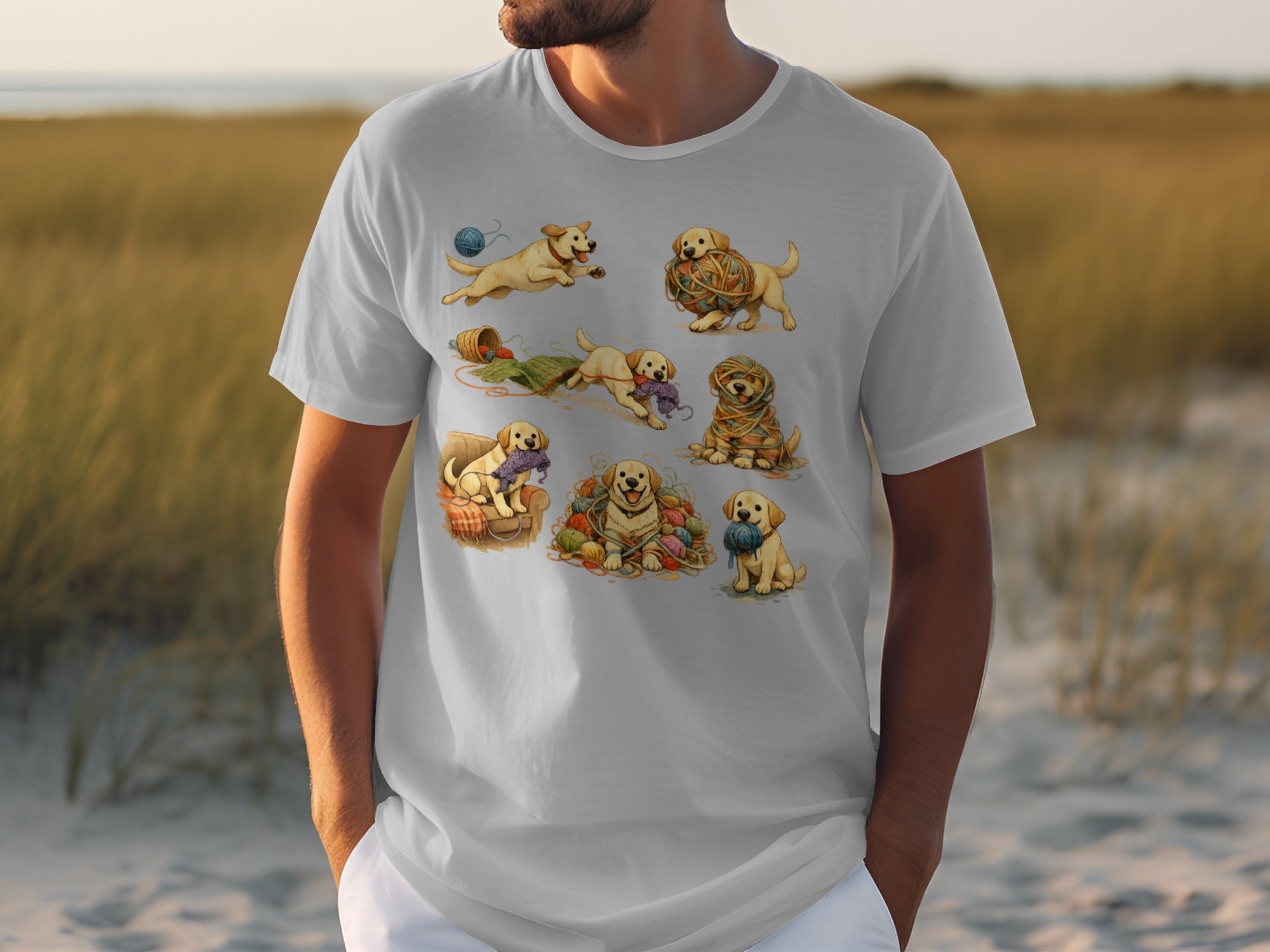 White t-shirt with a watercolor illustration of playful golden retriever puppies interacting with balls of yarn.