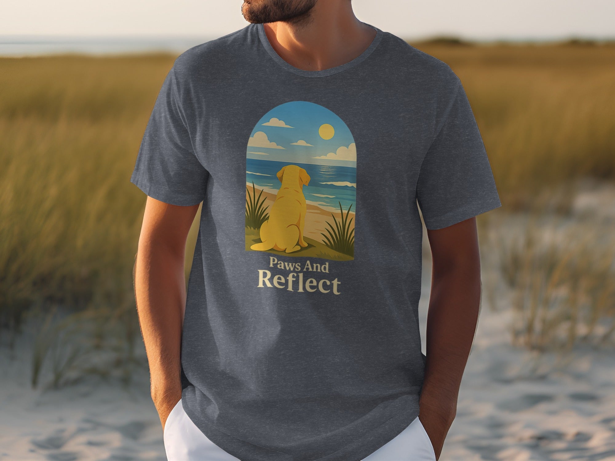 Dark t-shirt with a graphic of a yellow dog looking at the ocean and text "Paws And Reflect".