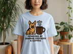 Light blue t-shirt with cartoon German Shepherd and coffee mug graphic, text reads "Powered by German Shepherd & Coffee".