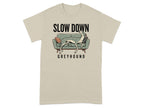 Beige t-shirt with a greyhound relaxing on a couch, text reads "SLOW DOWN GREYHOUND".