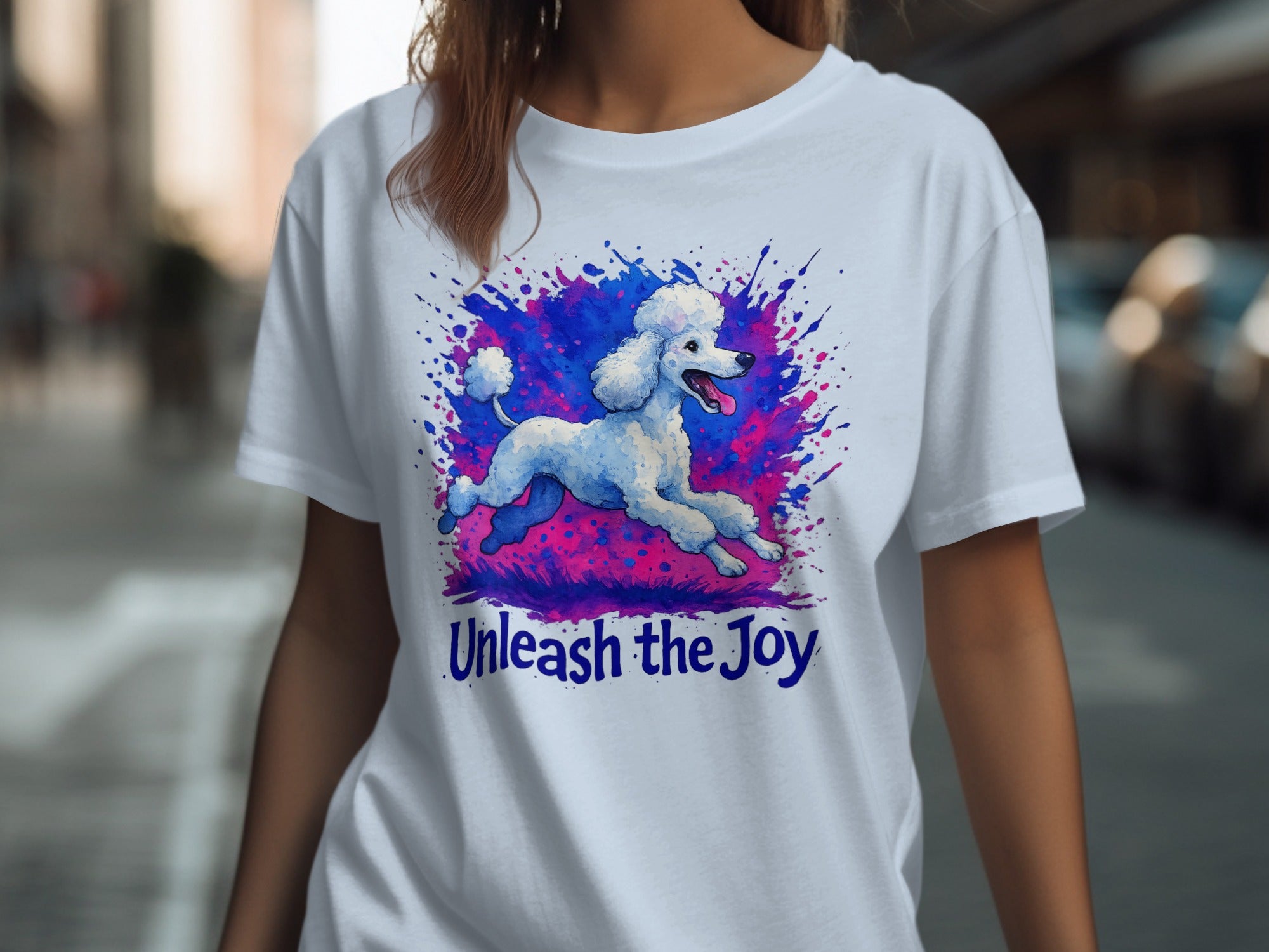 White t-shirt with watercolor poodle and pink/blue ink splatters, text "Unleash the Joy".