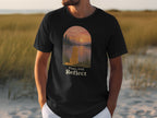 Black t-shirt with golden retriever looking at sunset over water, text "Paws And Reflect".