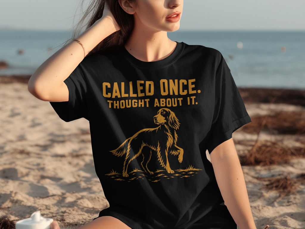 Black t-shirt with gold text "CALLED ONCE. THOUGHT ABOUT IT." and dog graphic.