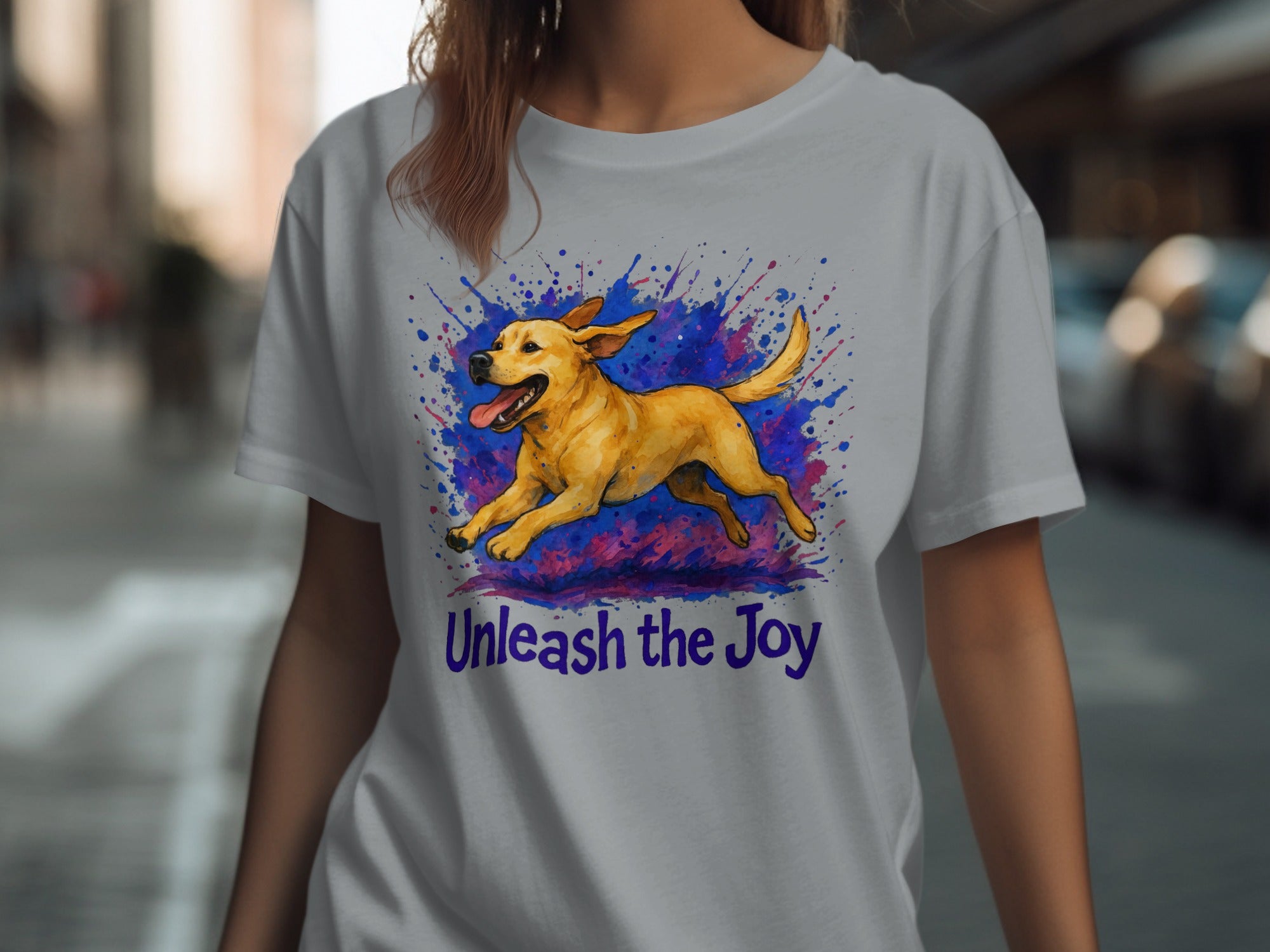Light gray t-shirt with a yellow dog mid-leap over purple and blue paint splashes, text below says "Unleash the Joy".