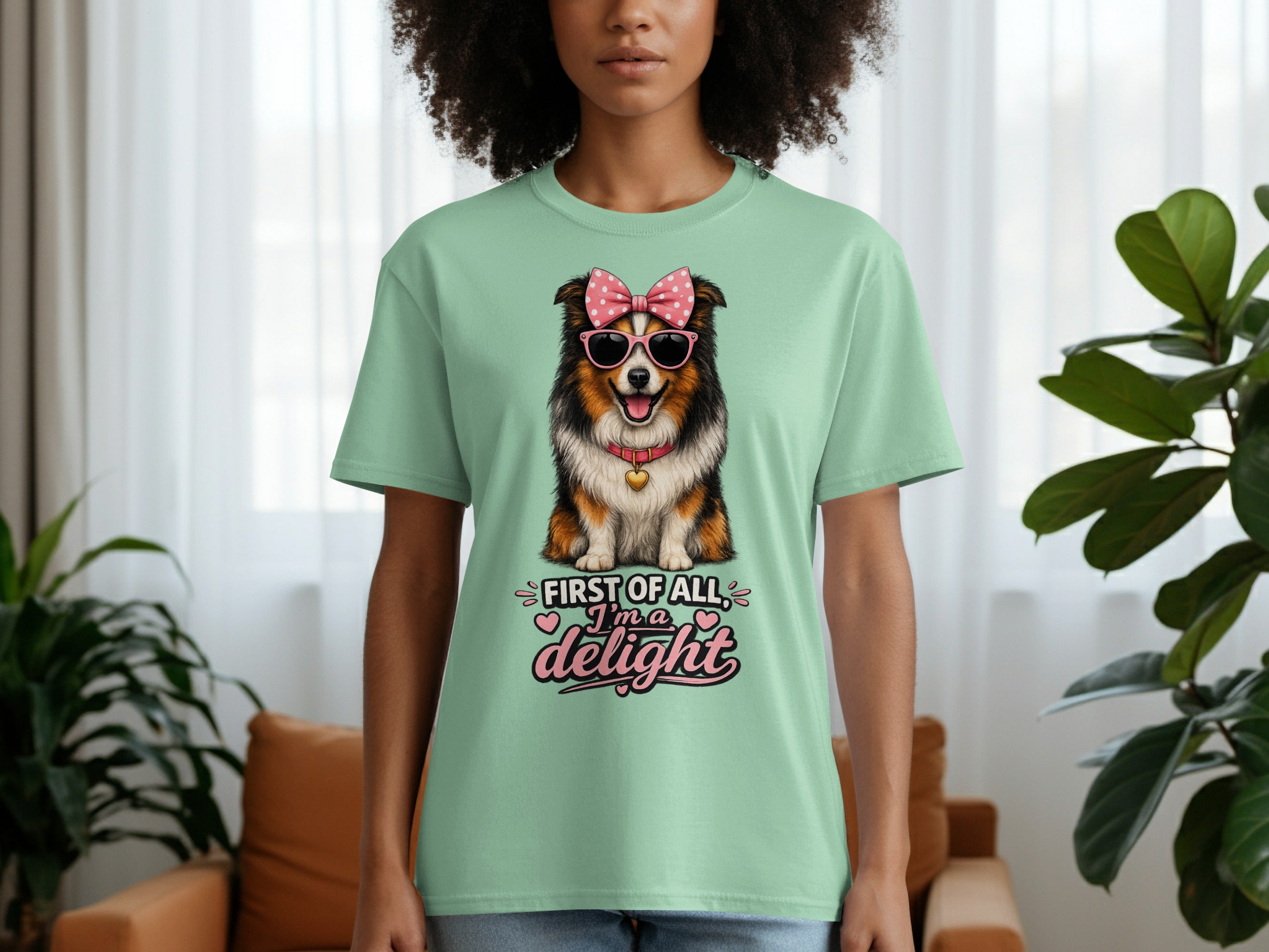 Light green t-shirt with a dog wearing sunglasses and a pink bow, saying "First of all, I'm a delight".