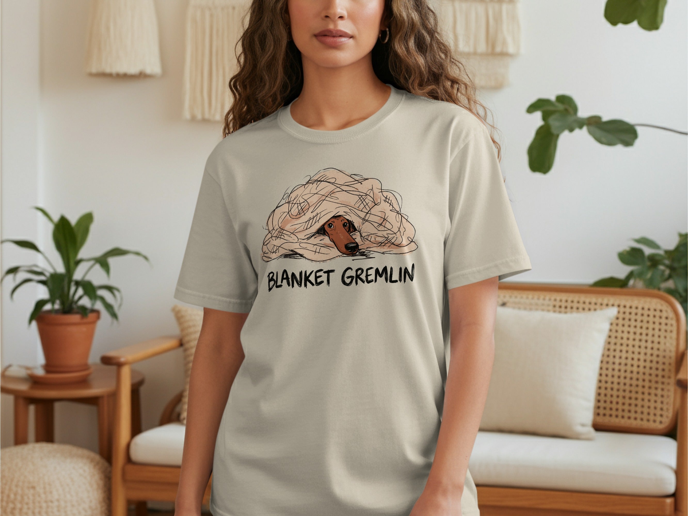 Cream t-shirt with illustration of a dog peeking out from under a blanket.