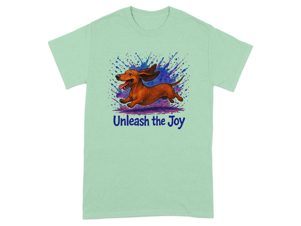 Light mint t-shirt with a watercolor illustration of a dachshund running with paint splatters and "Unleash the Joy" text.