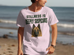 Light pink t-shirt with a German Shepherd graphic and text "STILLNESS IS DEEPLY SUSPICIOUS."