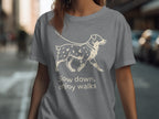 Grey t-shirt with line art of a dog on a leash and text "Slow down, enjoy walks".