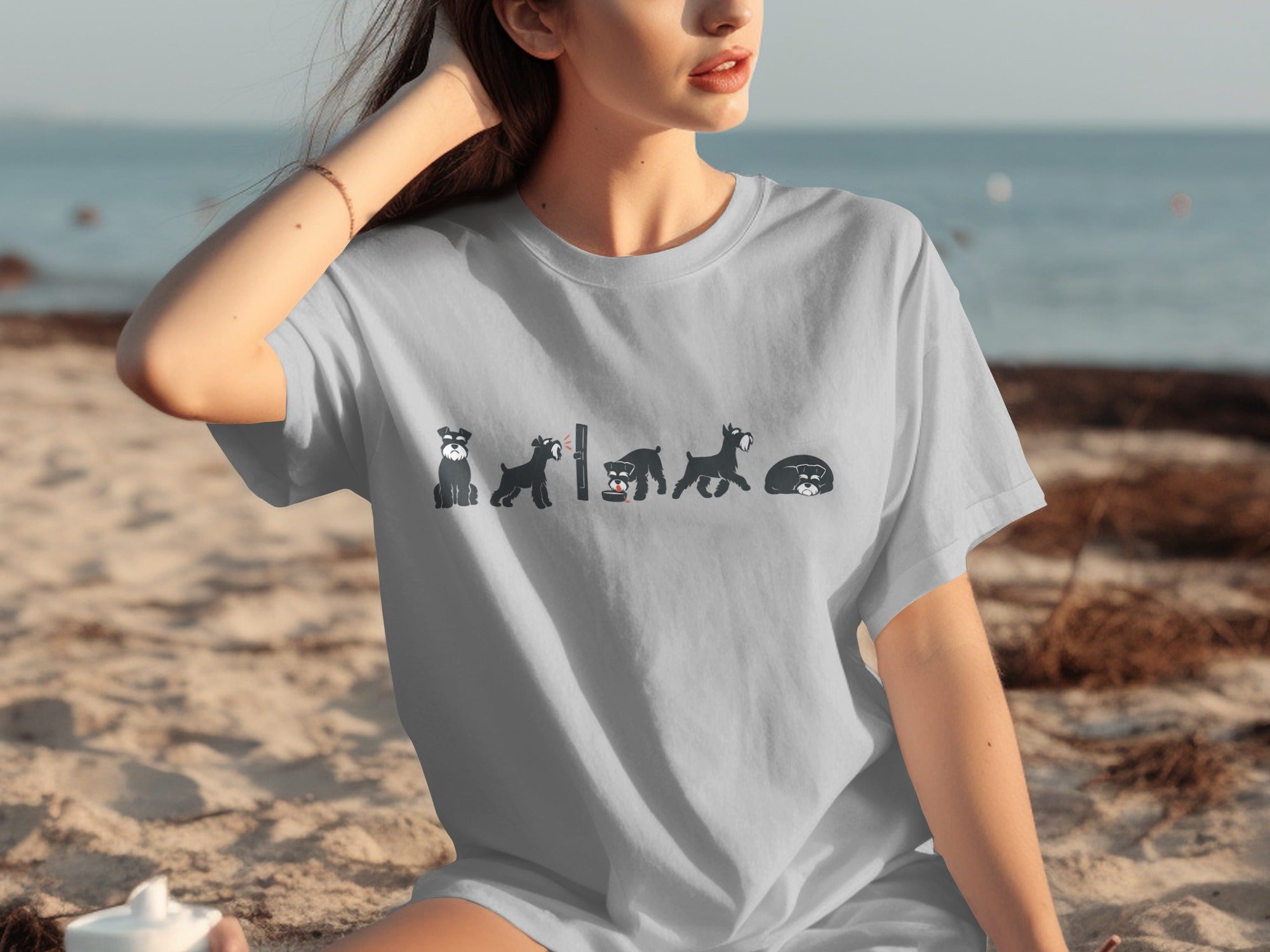 T-shirt with cartoon Schnauzer evolution graphic on a beach background.