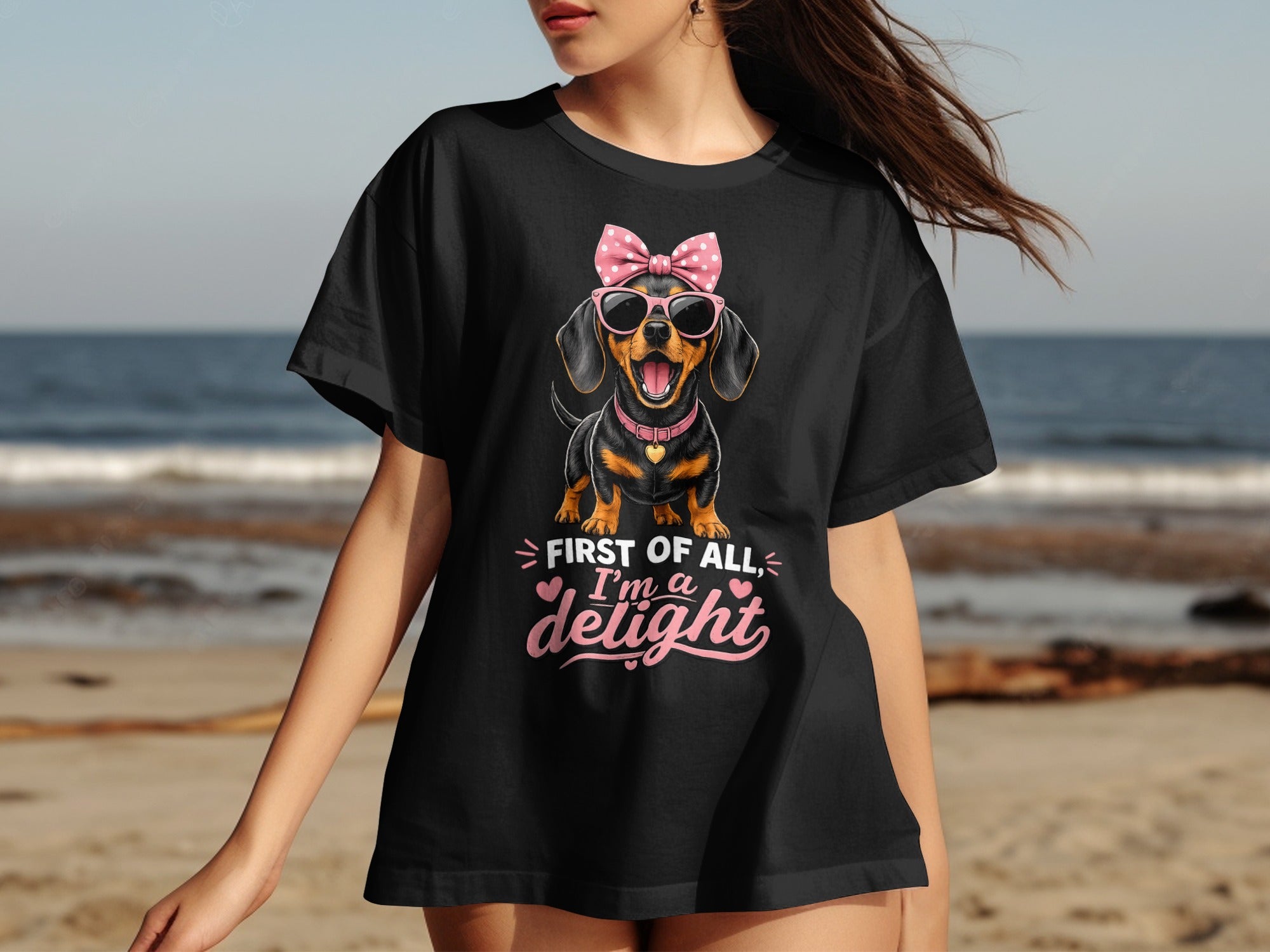Black t-shirt with a dachshund wearing sunglasses and a bow saying "First of all, I'm a delight".