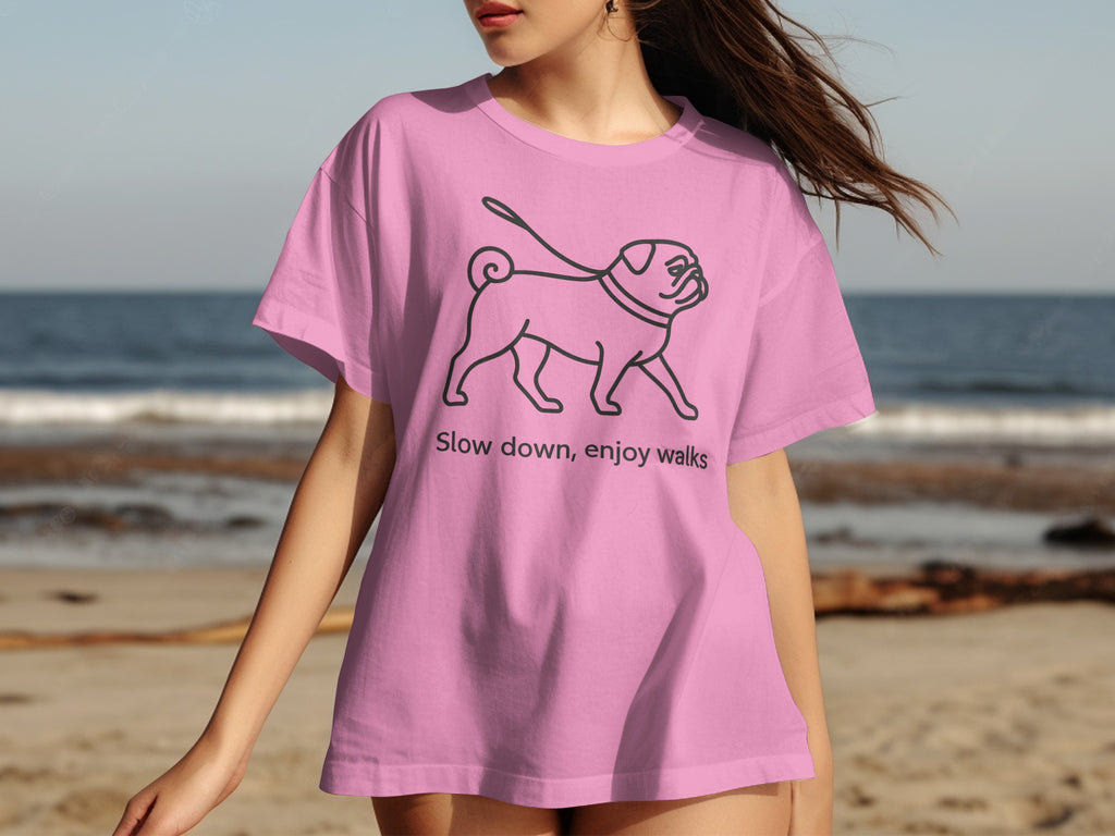 Pink t-shirt with sketched pug on a leash and text "Slow down, enjoy walks."