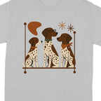 Three brown and white spotted dogs sit on a shelf with decorative elements.