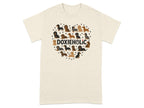 Dachshunds form a heart shape above the text DOXIEHOLIC on a cream t-shirt.
