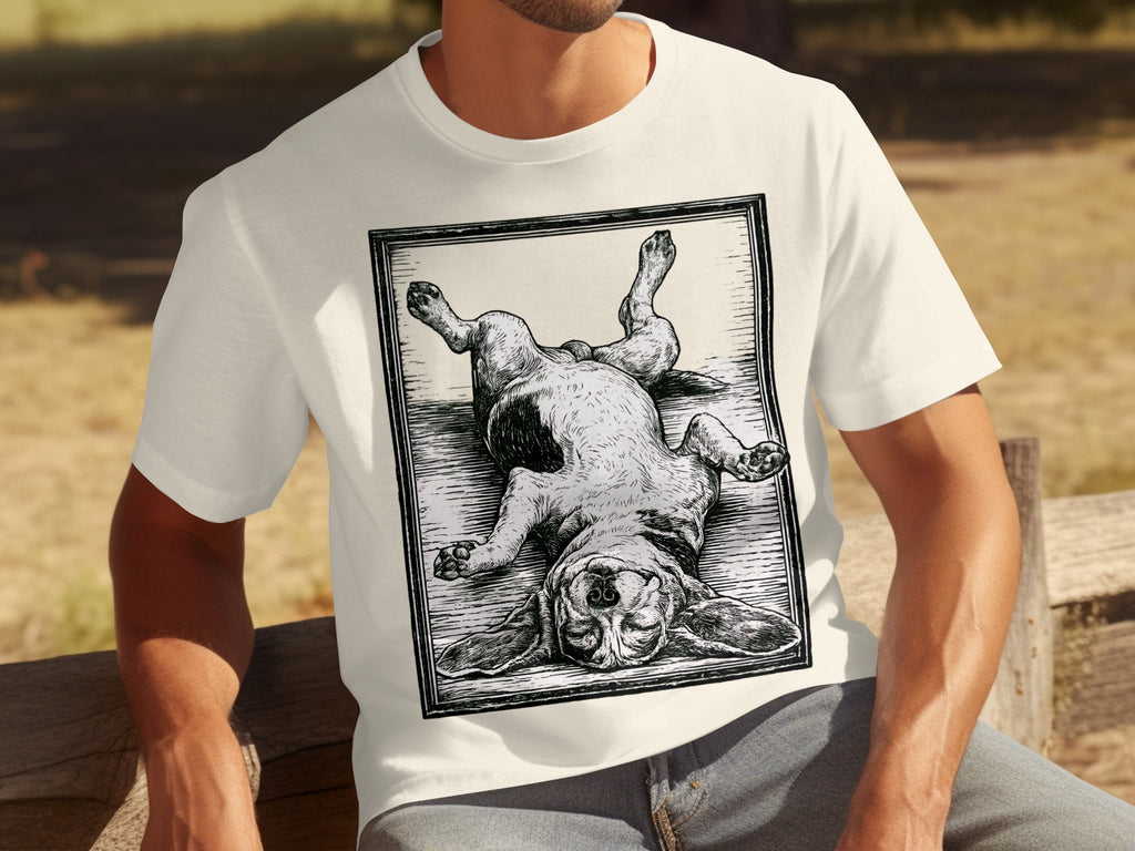 Cream t-shirt with a black and white woodcut-style print of a basset hound lying on its back.