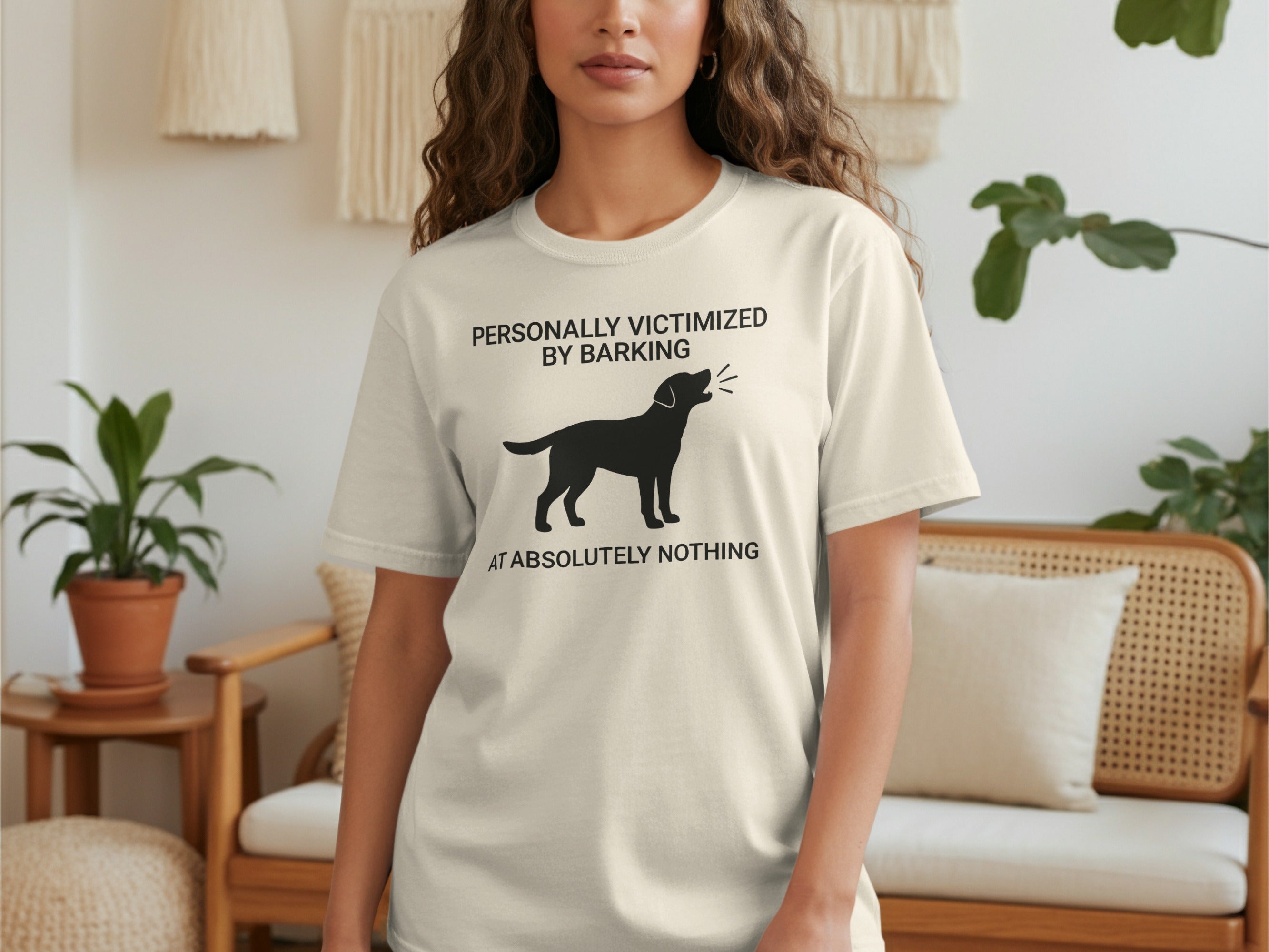 Cream t-shirt with black dog silhouette and text "Personally victimized by barking at absolutely nothing".