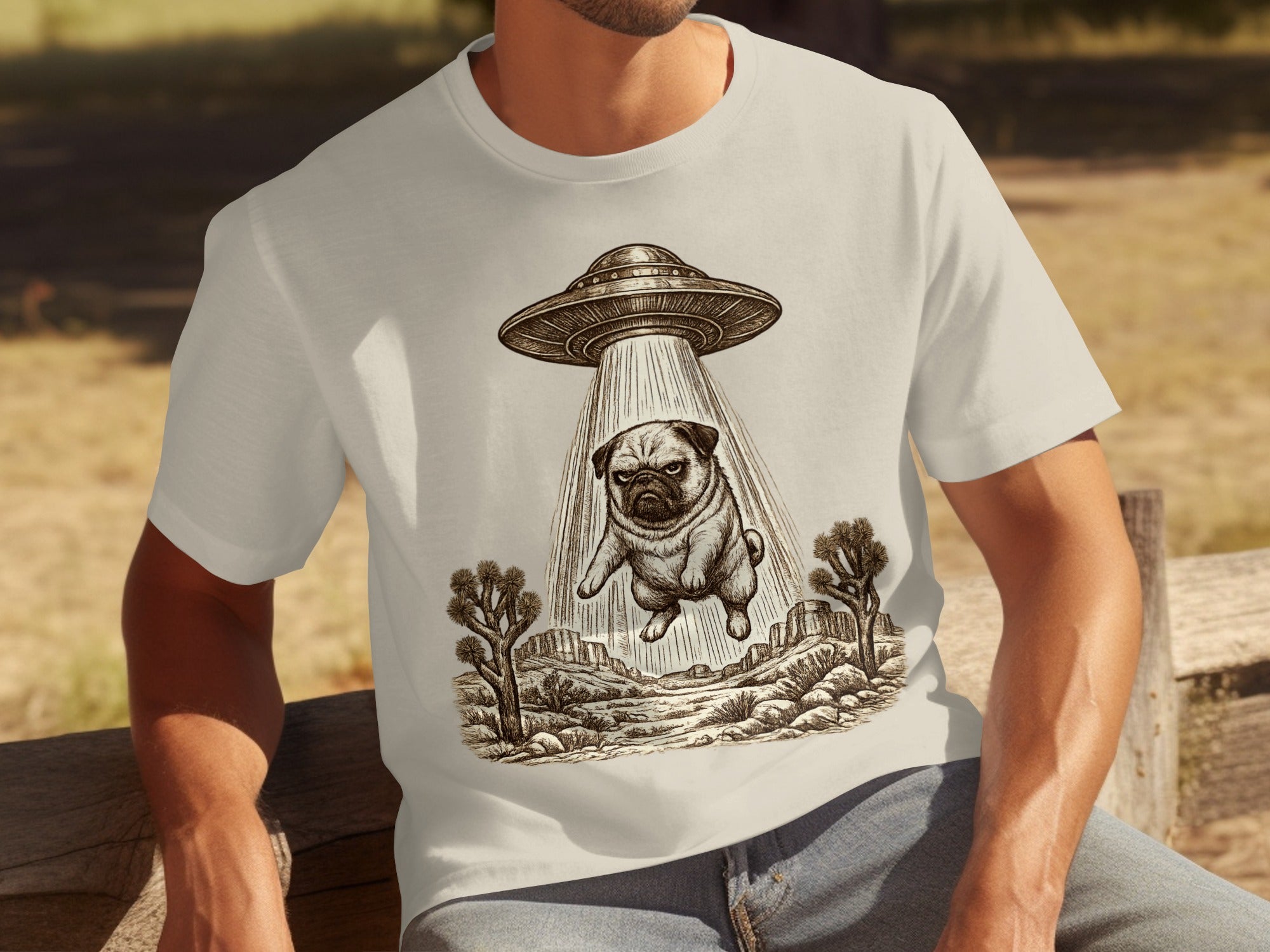 T-shirt with pug being abducted by a UFO in a desert landscape drawing.