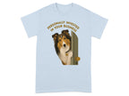Collie peeking through an open door, wearing a pendant, on a light blue t-shirt.