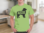 Black silhouette of an Australian Shepherd dog with "AUSSIE" text on a light green t-shirt.