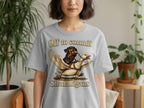 Grey t-shirt with illustration of a dog riding a duck, text "Off to commit Shenanigans".